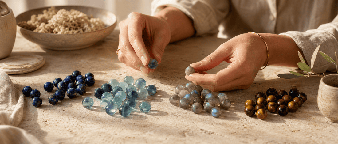 Hands comparing naturally varied lapis lazuli, fluorite, moonstone and tiger's eye beads