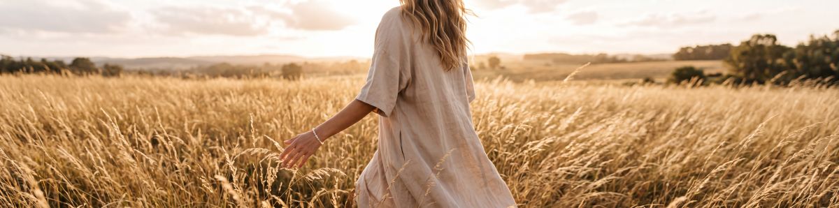 Woman walking through a golden sunlit field wearing a crystal bracelet for Lumiclay's crystal bracelet collection