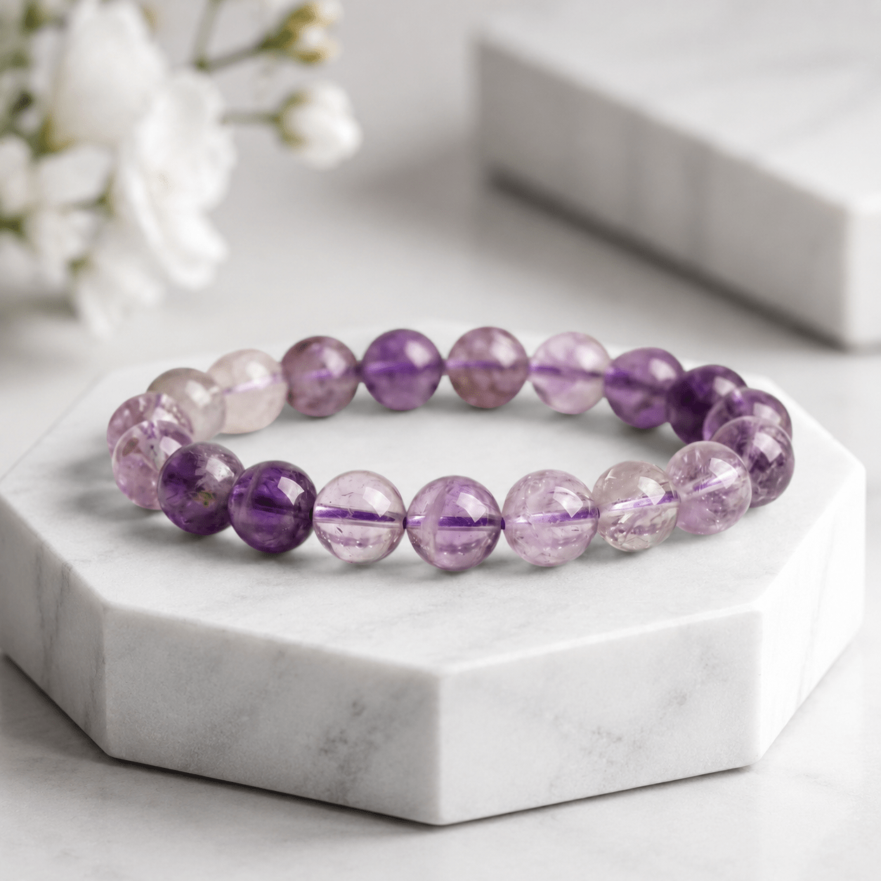 A Quiet Return Amethyst bracelet displayed on white marble with soft floral styling