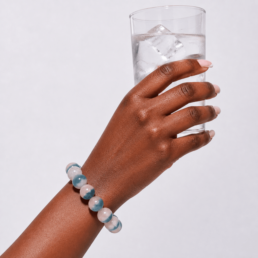 Blue Fluorite bracelet worn while holding a clear glass of ice water
