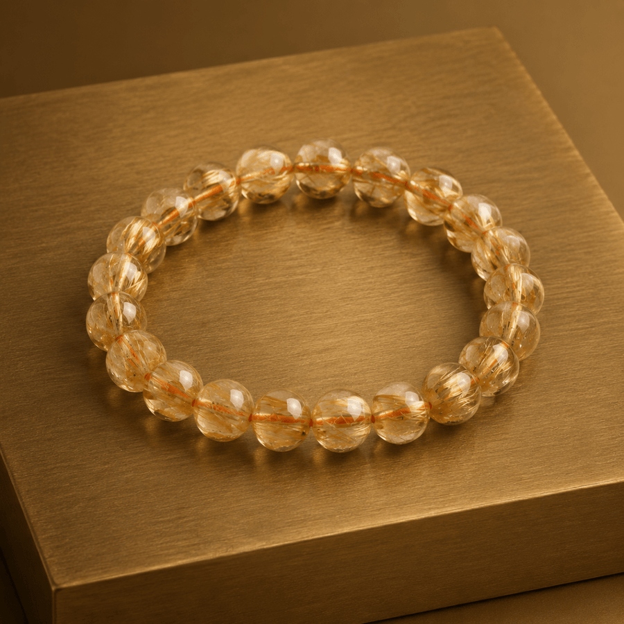 Golden Rutilated Quartz citrine bracelet displayed on a warm gold surface