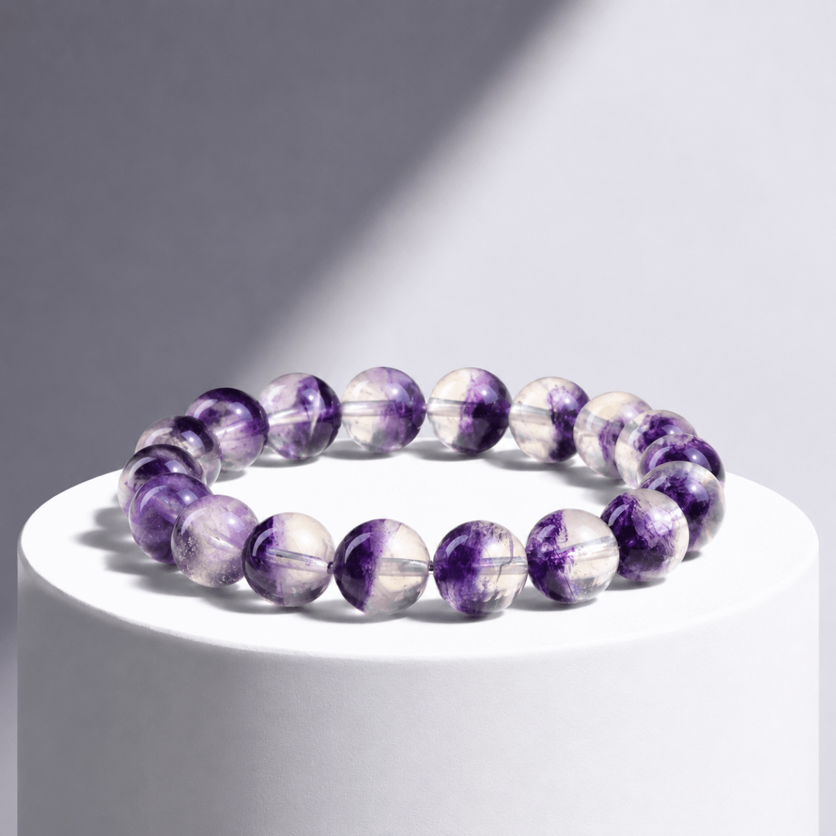 Natural Purple Fluorite bracelet displayed on a white pedestal in directional light