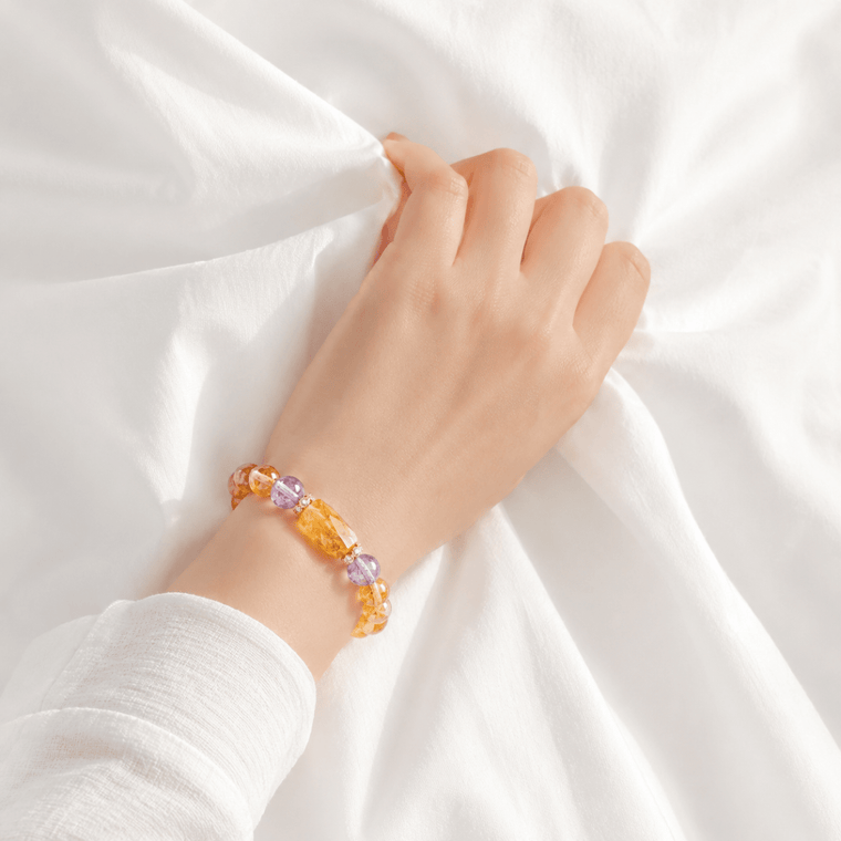 Citrine and Amethyst bracelet worn on wrist against soft white bedding