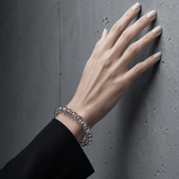 Woman wearing I Am Protected Black Rutilated Quartz bracelet against black satin fabric