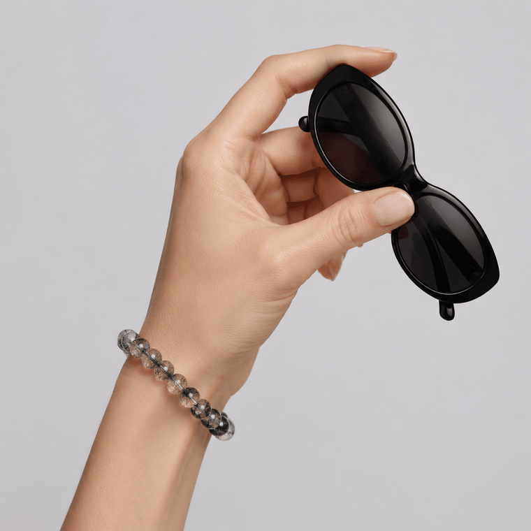 I Am Protected 7A Black Rutilated Quartz bracelet worn on wrist while holding black sunglasses