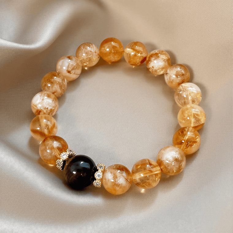 Top view of I Am Ready Yellow Tower Citrine bracelet with Tiger Eye centerpiece on champagne satin