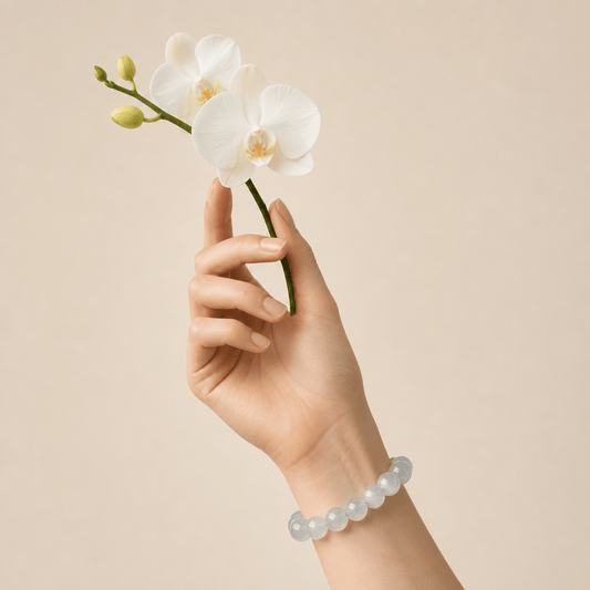 White Moonstone bracelet worn on wrist while holding a white orchid flower