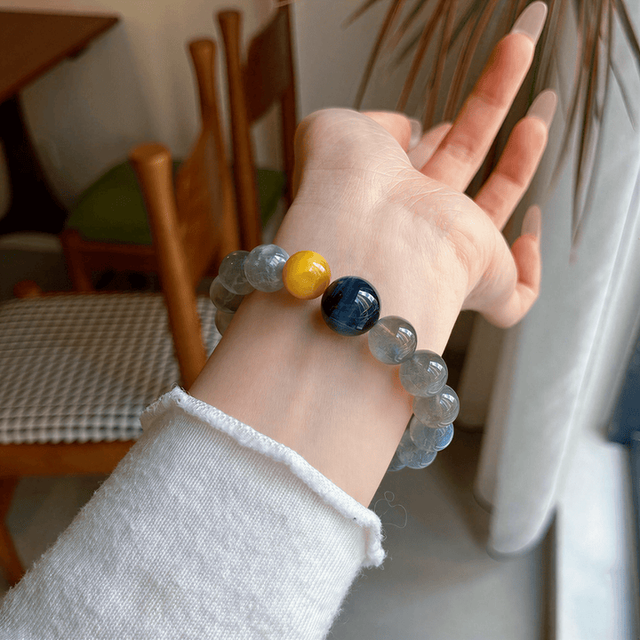 Gray Moonstone and Tiger Eye bracelet worn on wrist beside a bright window