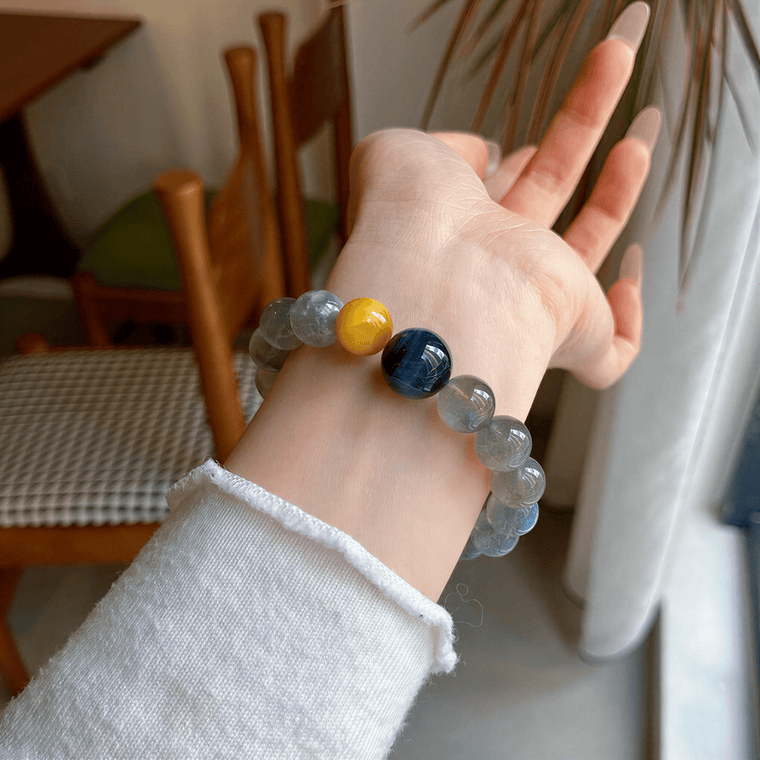 Gray Moonstone and Tiger Eye bracelet worn on wrist beside a bright window