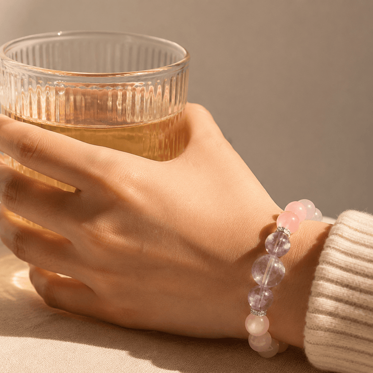 Woman wearing I Let Love In Rose Quartz bracelet with Amethyst accents while holding a glass of tea