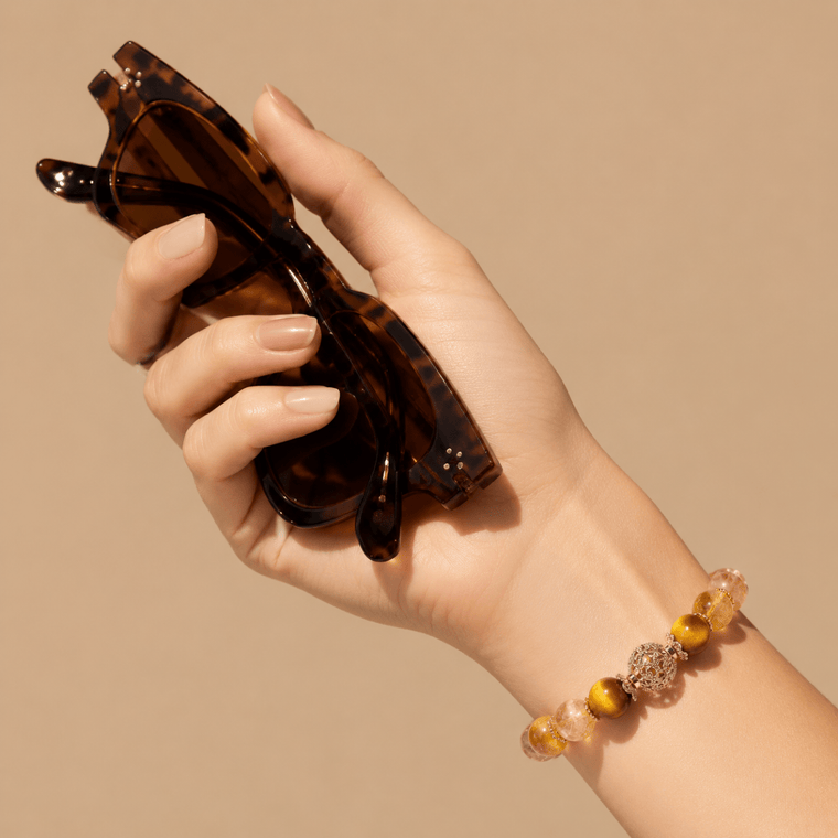 Natural Citrine and Tiger's Eye bracelet worn on wrist while holding tortoise sunglasses in warm sunlight