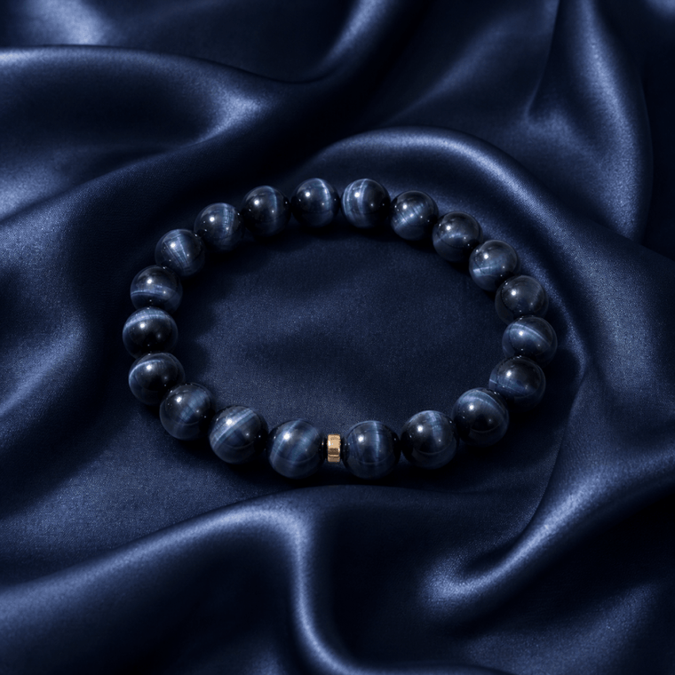 Blue Tiger's Eye bracelet displayed on navy satin fabric with a single gold-tone accent
