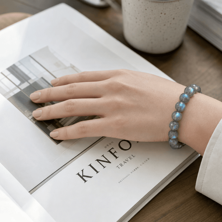 Blue Flash Gray Moonstone bracelet worn on wrist while holding a clear glass of water
