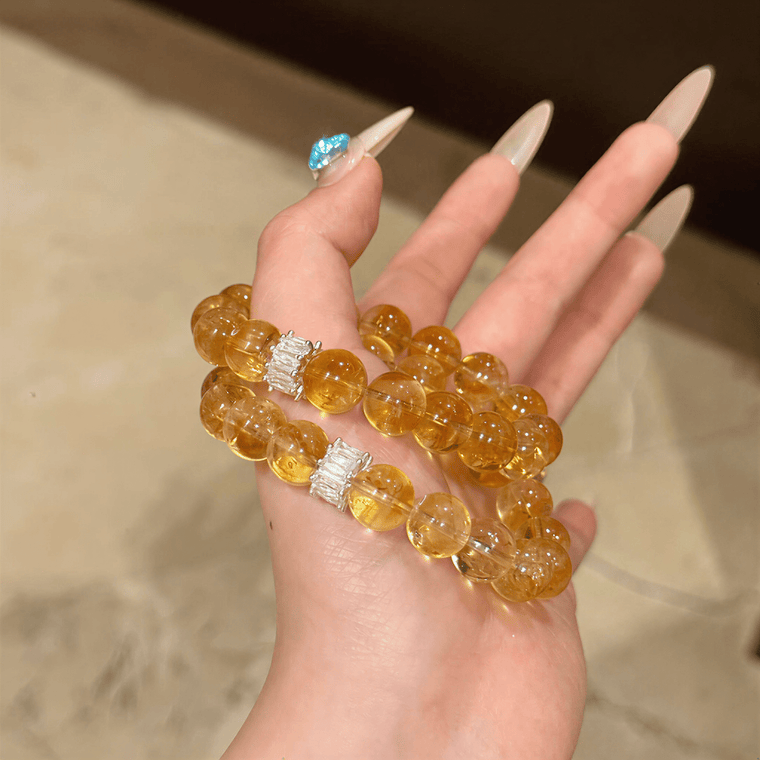 Two I Welcome More Citrine bracelets held in hand with golden crystal beads and clear focal accents