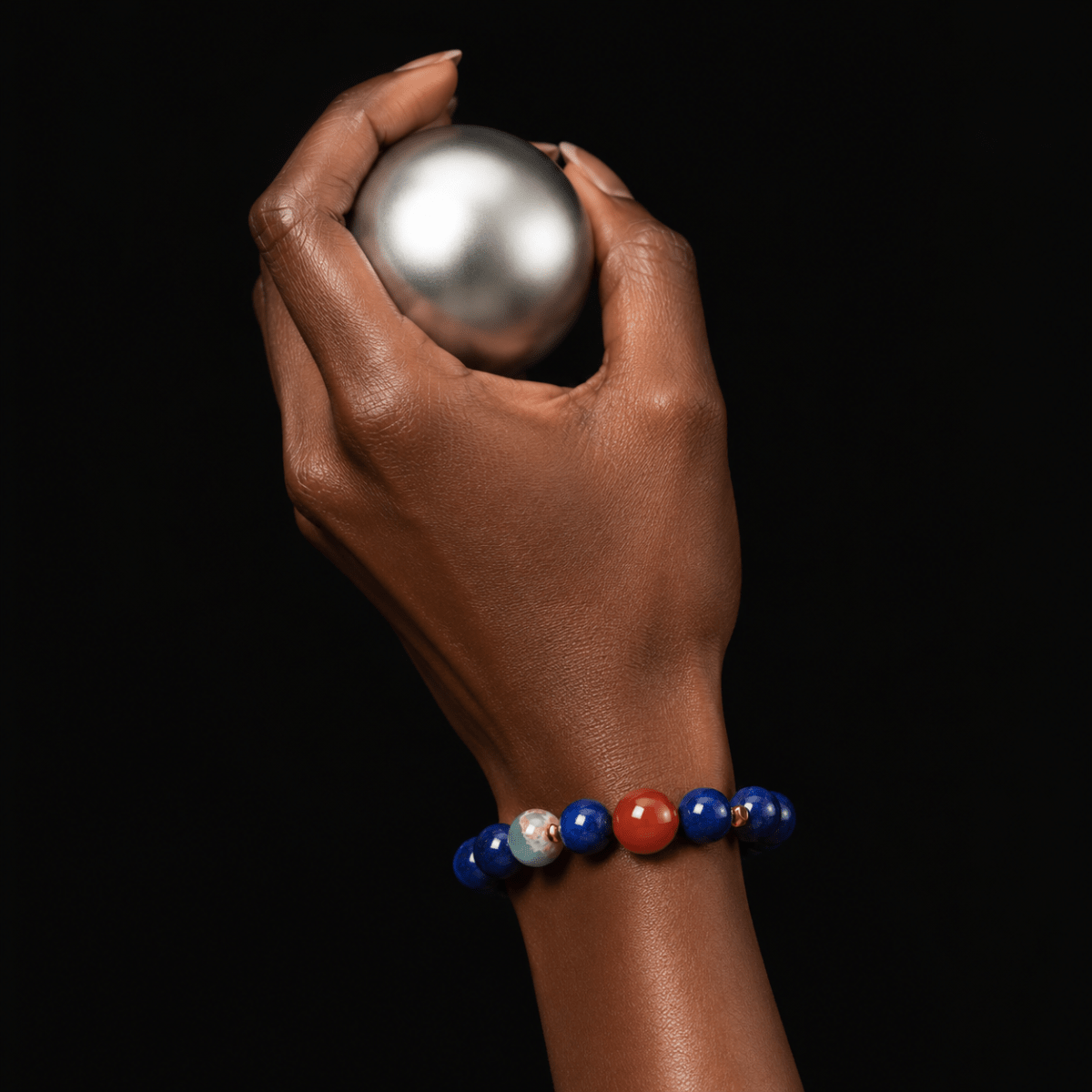 Model wrist wearing Lapis Lazuli bracelet with Nanhong Agate focal bead and gold-tone spacer accents