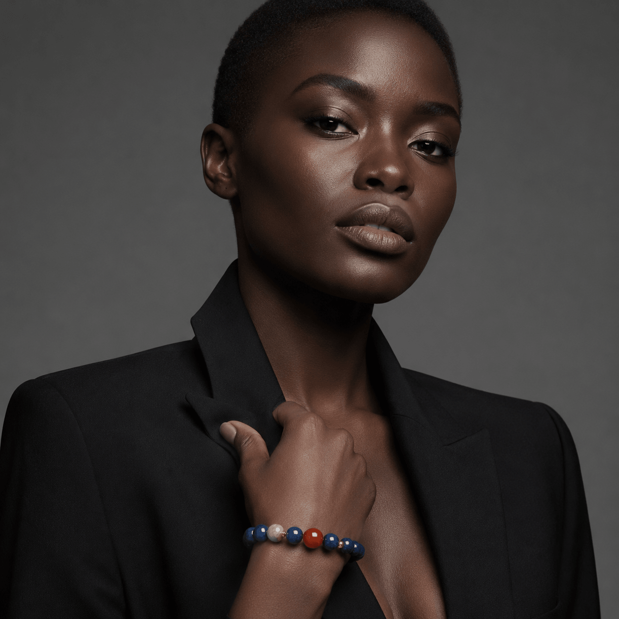 Model wearing an 8mm Lapis Lazuli bracelet with red Nanhong focal bead and gold-tone accents