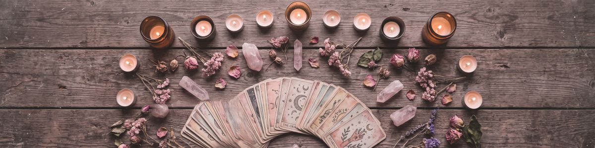 Tarot cards, rose quartz crystals, dried flowers, and candles arranged for an intention ritual