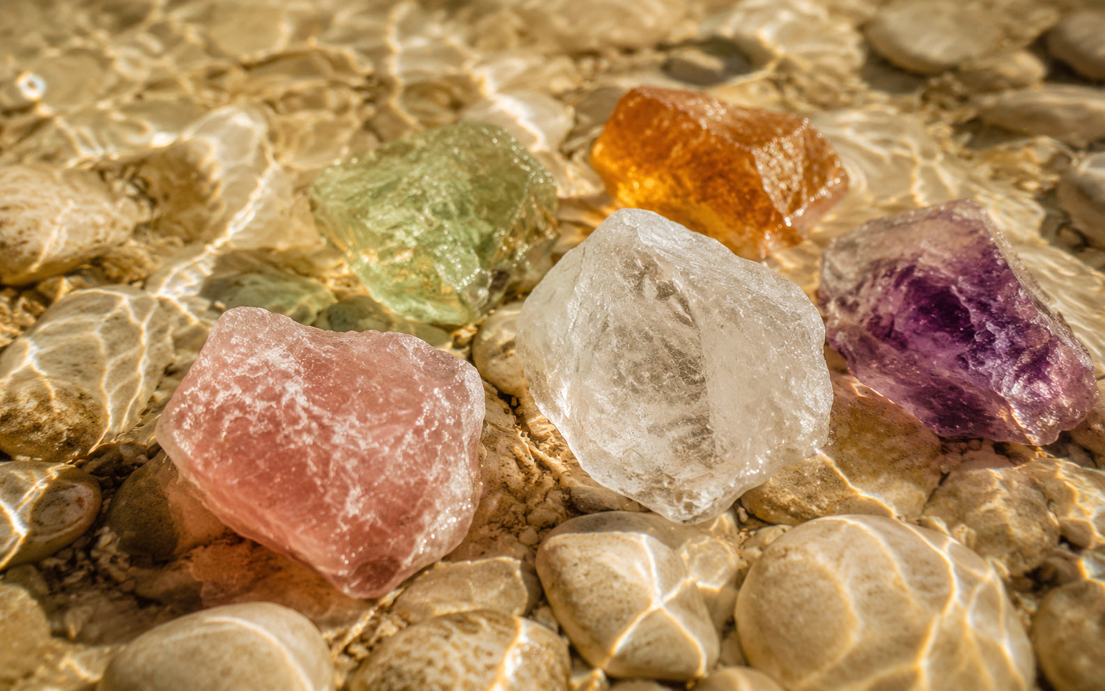Natural crystals resting in clear water over river stones