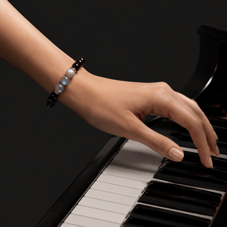Woman wearing My Energy Is Mine Obsidian and Gray Moonstone bracelet while playing piano