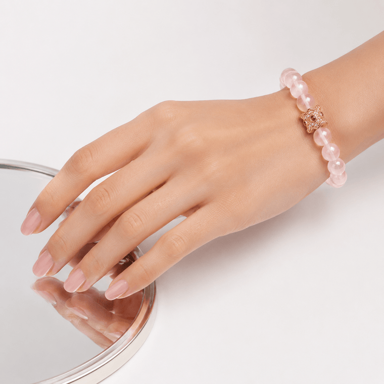 Close-up of My Heart Is Safe natural Rose Quartz bracelet worn on wrist beside a mirror