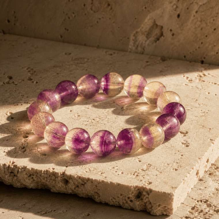 14mm Purple Fluorite bracelet displayed on warm stone in natural sunlight