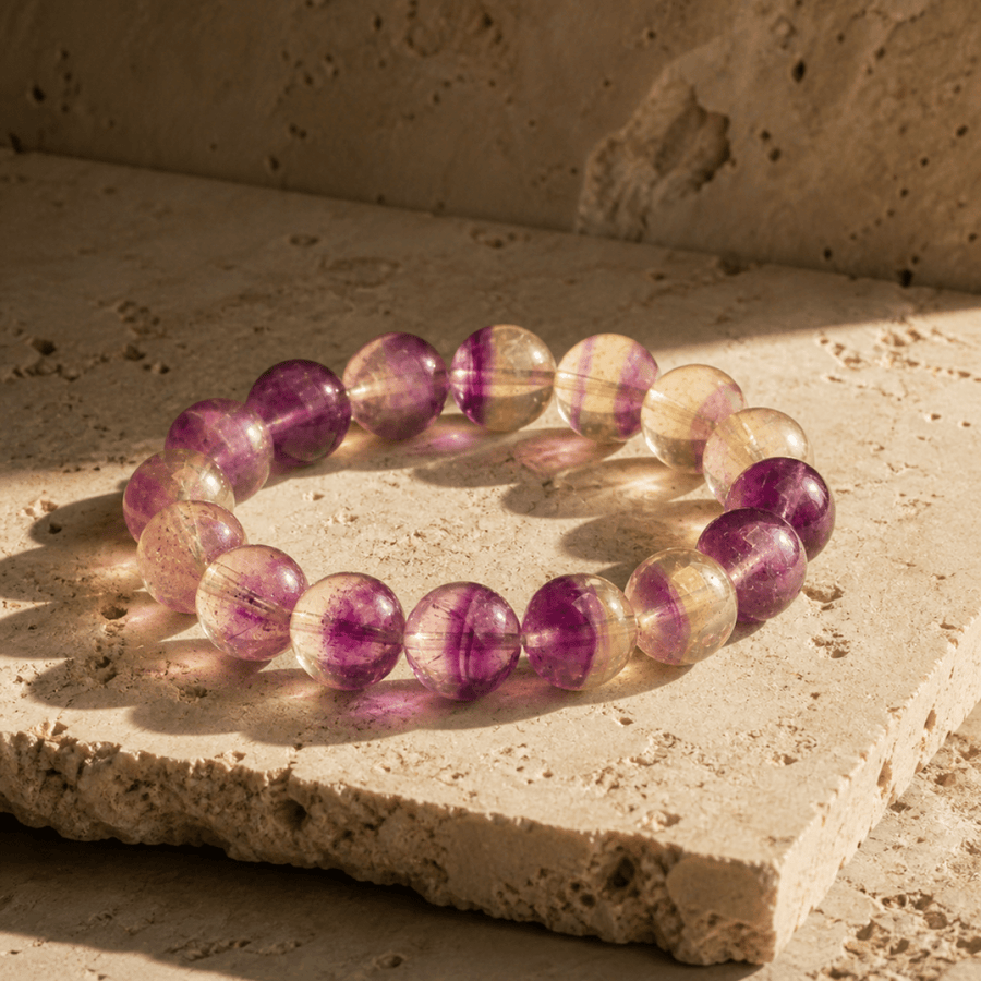 14mm Purple Fluorite bracelet displayed on warm stone in natural sunlight