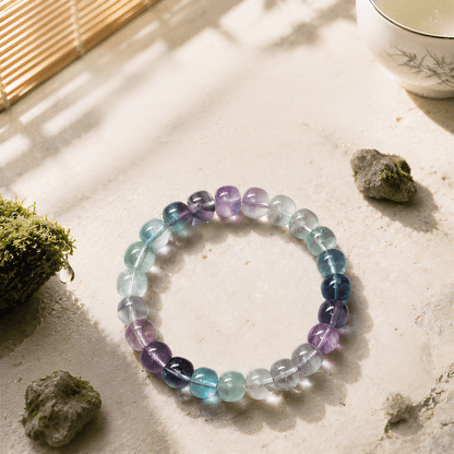 High-clarity Rainbow Fluorite bracelet displayed with moss and stones in sunlight