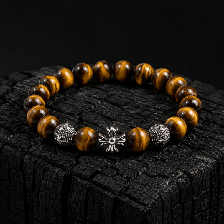 Natural Tiger's Eye bracelet with silver-tone cross displayed on black charcoal wood