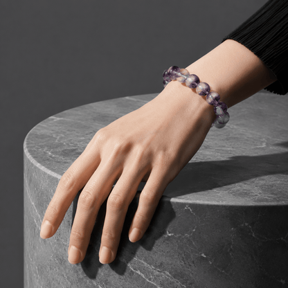 Purple Fluorite bracelet worn with a black sleeve beside a dark stone surface