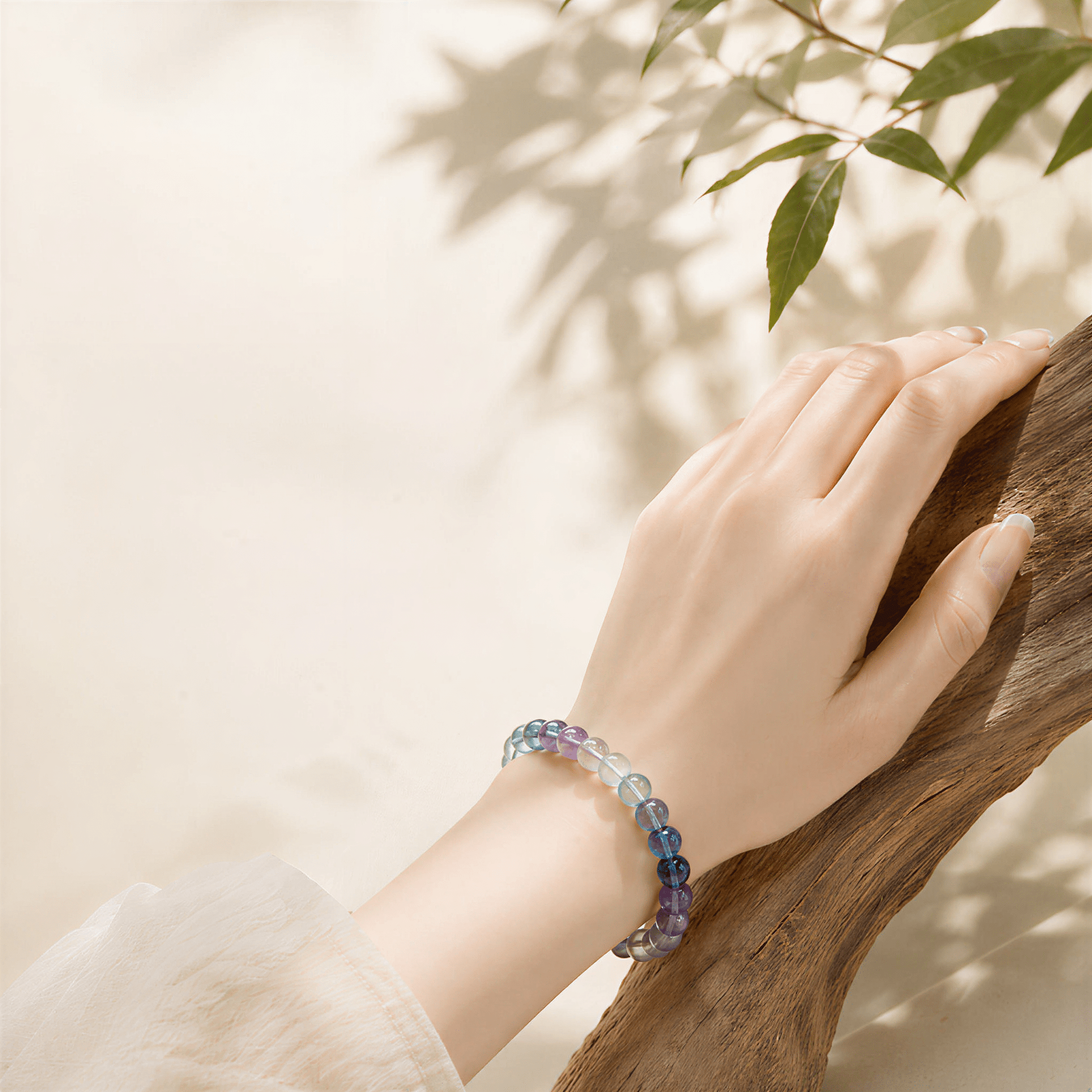 Natural Rainbow Fluorite bracelet worn beside wood and green leaves outdoors