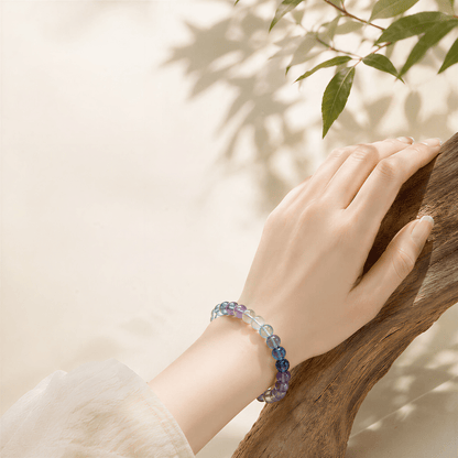 Natural Rainbow Fluorite bracelet worn beside wood and green leaves outdoors
