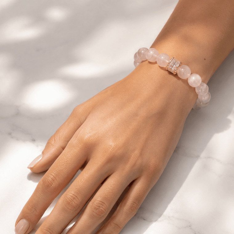 Close-up of hand wearing Soft Devotion Rose Quartz bracelet in soft natural light