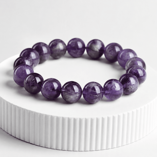 The Stillness Within Amethyst bracelet displayed on a white pedestal with deep purple 12mm beads