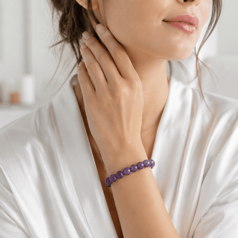 Woman wearing The Stillness Within 12mm Amethyst bracelet with a white robe