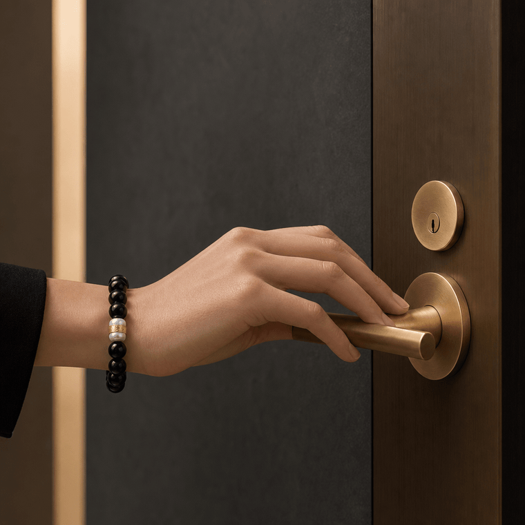 Woman wearing The Way Opens Obsidian mantra bracelet while opening a brass door handle