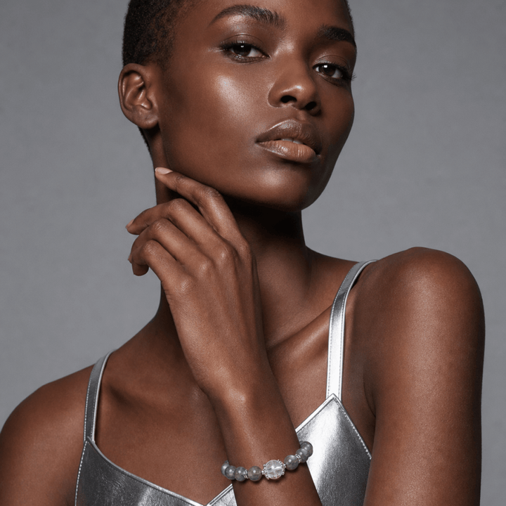 Model wearing Blue Gray Moonstone and Clear Quartz bracelet with a silver outfit in a modern studio setting