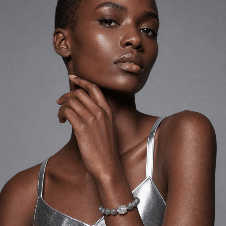 Model wearing Blue Gray Moonstone and Clear Quartz bracelet with a silver outfit in a modern studio setting