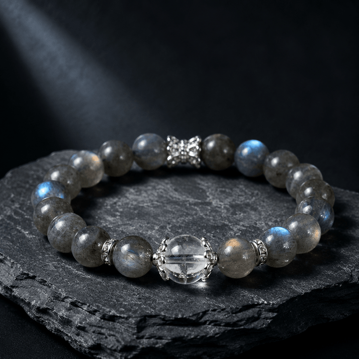 Blue Gray Moonstone and Clear Quartz bracelet displayed on black rock with silver-tone accent details
