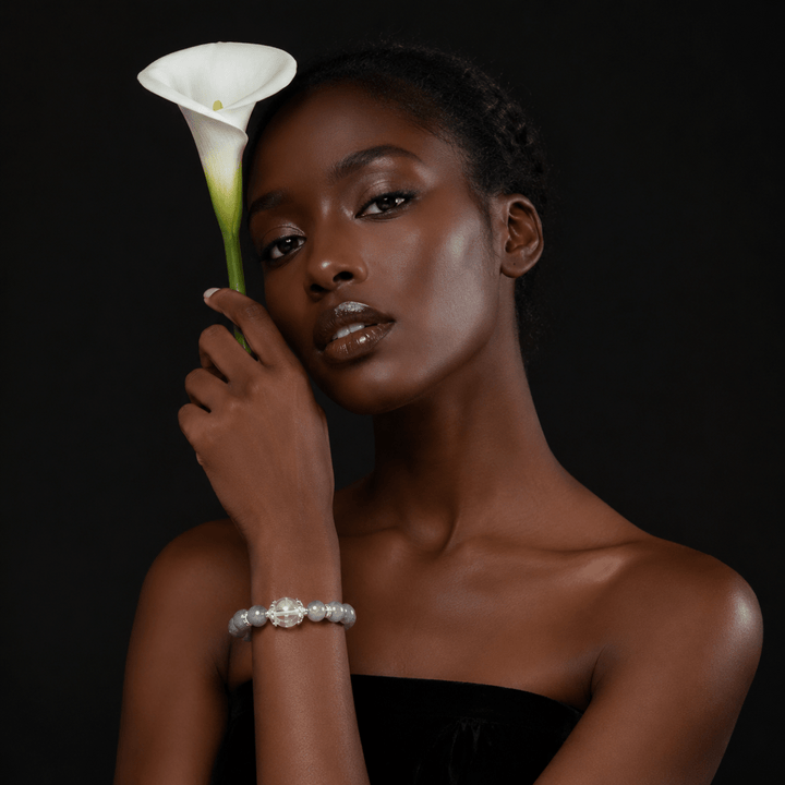 Model wearing Moonstone and Clear Quartz bracelet while holding a white calla lily against a dark background